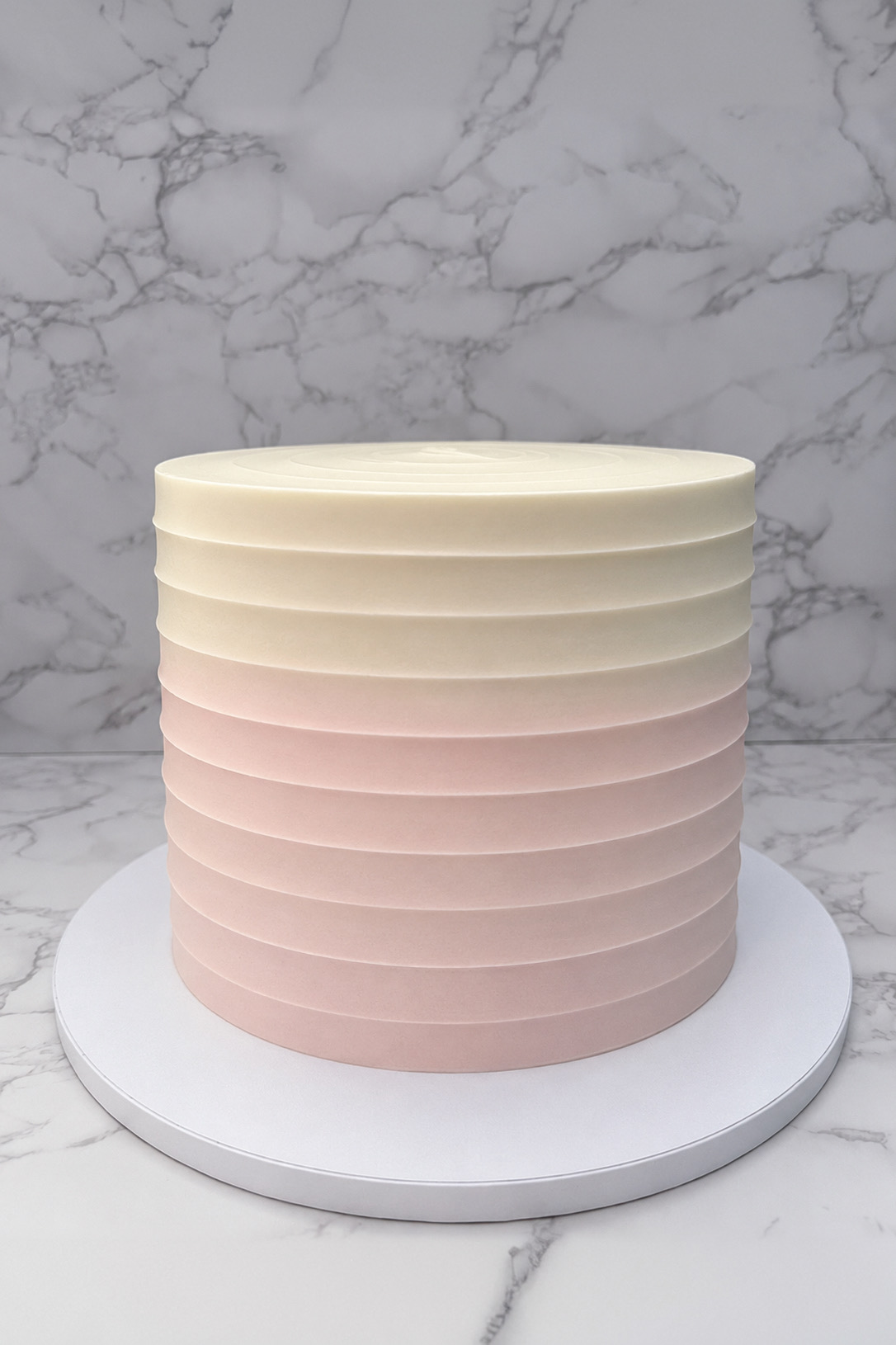 An elegant custom cake styled with delicate floral details on a soft ivory backdrop